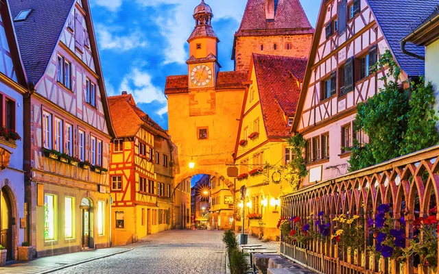 A Rothenburg lane at dusk with the lit Markus Tower ahead